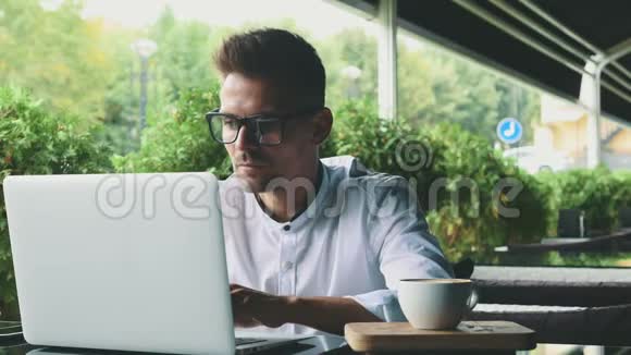 年轻的商人穿着商务服装戴着眼镜坐在咖啡馆里视频的预览图
