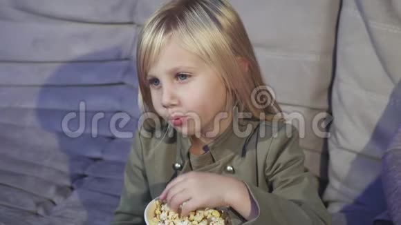 可爱的小女孩在电影院对着镜头笑着吃爆米花视频的预览图