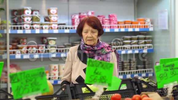 一位脸上有皱纹的老妇人在超市里挑选产品视频的预览图