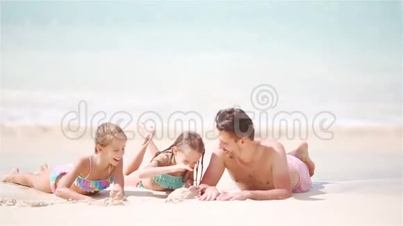父亲和孩子们躺在白色海滩上视频的预览图