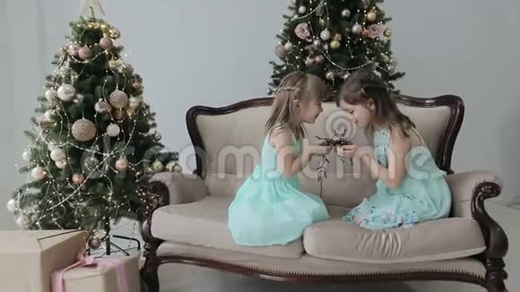 两个女孩坐在房子的地板上拿着圣诞礼物和一个花环女孩玩花环视频的预览图