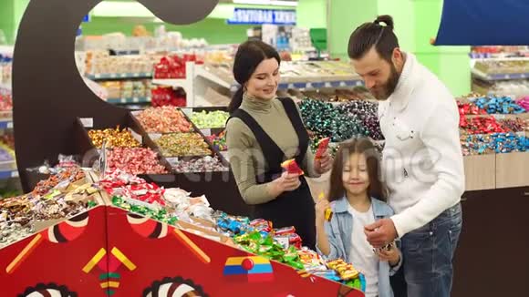 幸福的家庭和一个孩子在超市买糖果和糖果慢动作视频的预览图