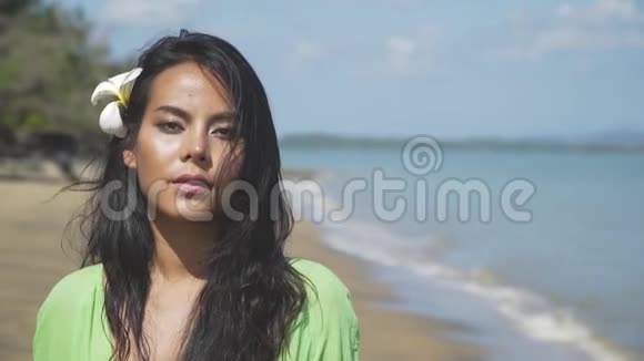 一个美丽的亚洲女孩穿着绿色连衣裙在海滩上散步视频的预览图