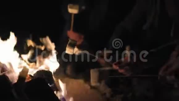 近距离观看手拿棍子与棉花糖并在晚上煎一群人坐在火边视频的预览图