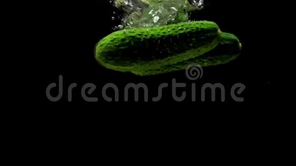 绿色黄瓜在黑色背景下落入透明水视频的预览图