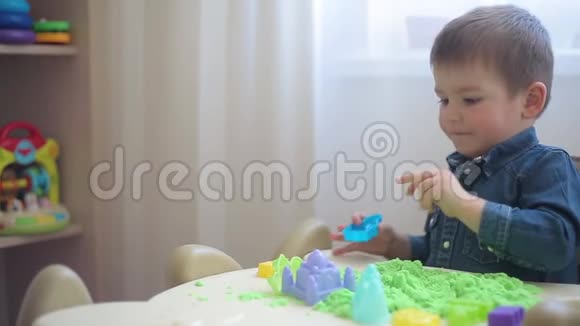 小男孩在绿色的沙滩城堡和塔楼上雕刻视频的预览图