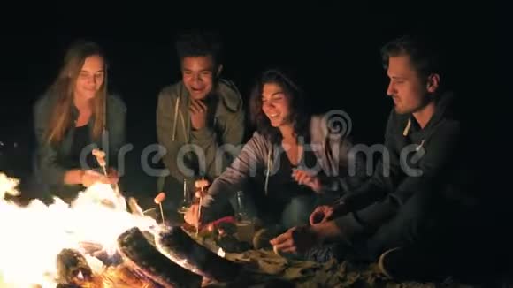 一群年轻的朋友深夜坐在炉火旁烤香肠喝啤酒聊天玩得开心视频的预览图
