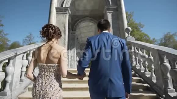 浪漫的年轻夫妇离开镜头来到美丽的拱门视频的预览图