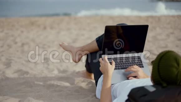 千禧游牧民在海滩上的笔记本电脑上工作视频的预览图