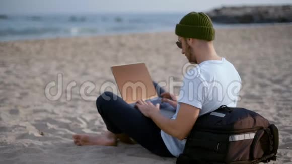 千禧游牧民在海滩上的笔记本电脑上工作视频的预览图