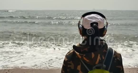 年轻人带着耳机面对广阔的大海巨浪和巨浪视频的预览图