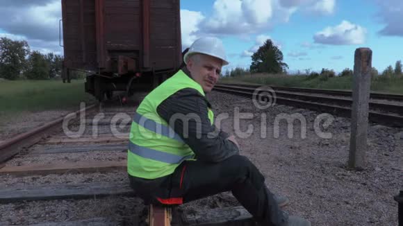 失望的铁路工人平板电脑坐在铁轨上视频的预览图