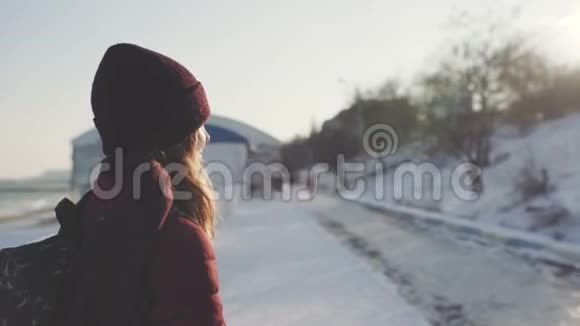 在冬天的公园里在白雪皑皑的背景和夕阳下一位年轻的美丽女子在户外的肖像视频的预览图