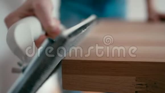 在家里夹着砂纸的木橡木桌上合上木工人砂光视频的预览图