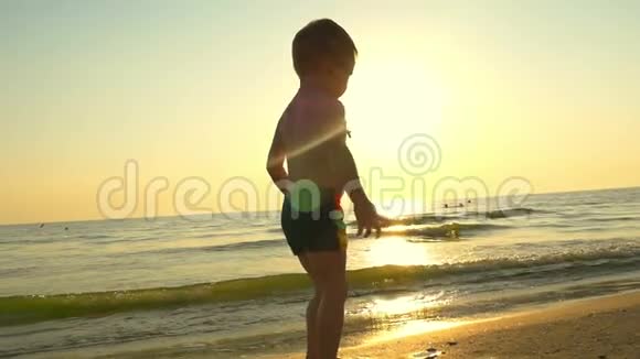 一个小男孩在沙滩上跳着跳着跑然后以缓慢的速度在水中溅起水花视频的预览图