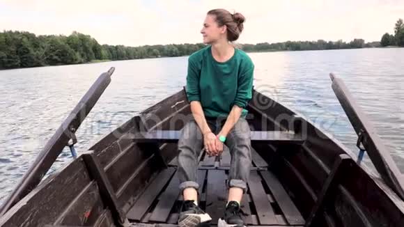 一个年轻漂亮的女人坐在湖上的船上视频的预览图