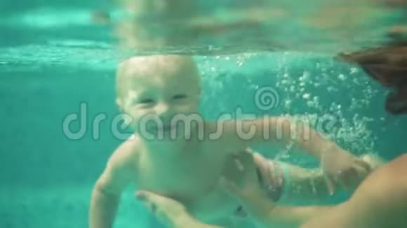 可爱的蹒跚学步的孩子和他的母亲一起在游泳池的水下游泳一次水下射击视频的预览图