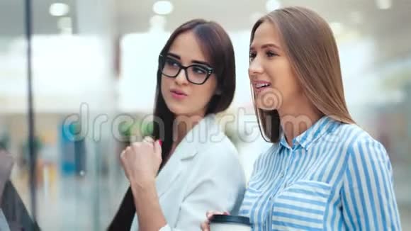 两个美女朋友在商场的店面后面讨论一些事情视频的预览图