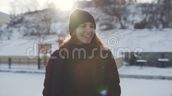在冬天的公园里在白雪皑皑的背景和夕阳下一位年轻的美丽女子在户外的肖像视频的预览图