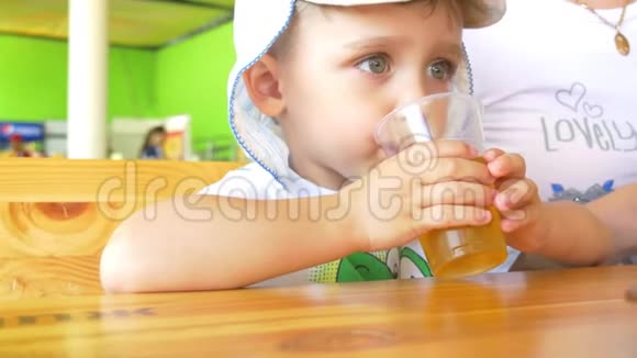 男孩正喝着一杯饮料坐在舒适的街头咖啡馆的桌子旁视频的预览图