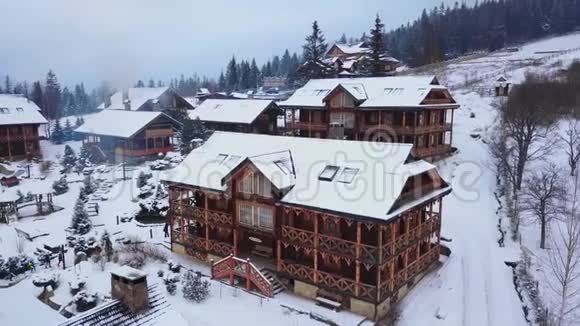山村木质小屋空中周围是针叶林雪覆盖的木屋的无人视野视频的预览图