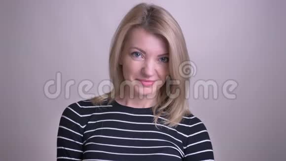 成年金发白种人女性的特写镜头带着害羞的笑容看着背景的镜头视频的预览图