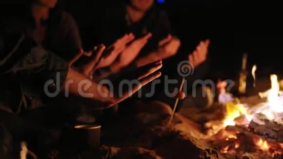 傍晚时分成群结队的青年男女坐在篝火旁双手热身交谈视频的预览图