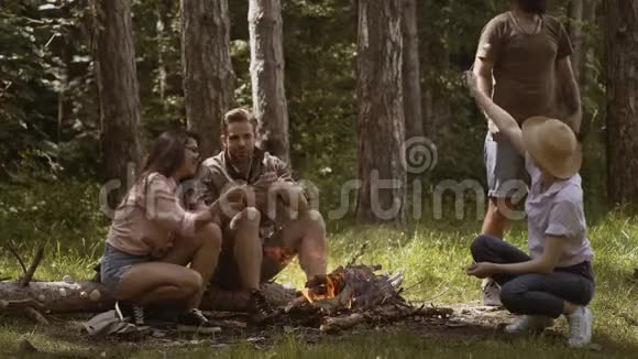 一群朋友在篝火上烤棉花糖朋友们晚上在火上烤着甜棉花糖视频的预览图