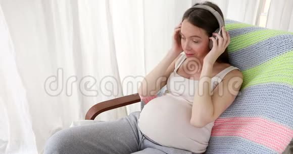 快乐的孕妇和婴儿一起听音乐视频的预览图