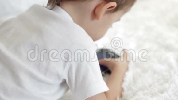 一个孩子躺在沙发上玩智能手机的特写镜头模糊的摄像机焦点视频的预览图