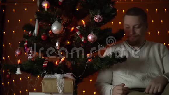 一个年轻人在圣诞树下打开一个礼盒视频的预览图