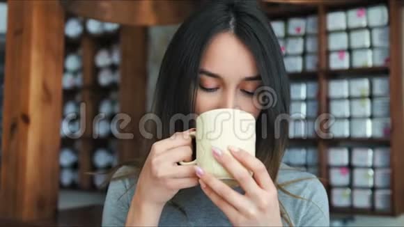 在咖啡馆喝茶或咖啡的漂亮女孩美女模特拿着一杯热饮料视频的预览图