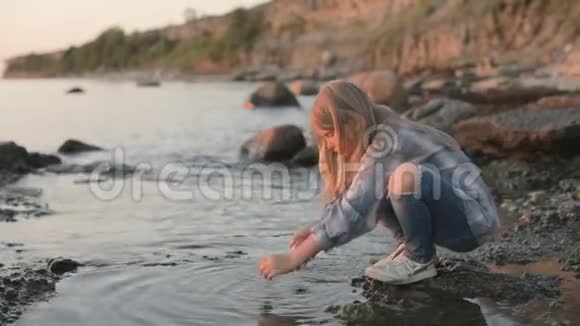 一个小女孩在海边用海水洗她的手和脸视频的预览图