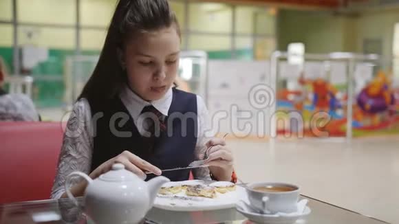 穿着校服的少女坐在学校食堂的桌子旁吃蛋糕喝茶视频的预览图