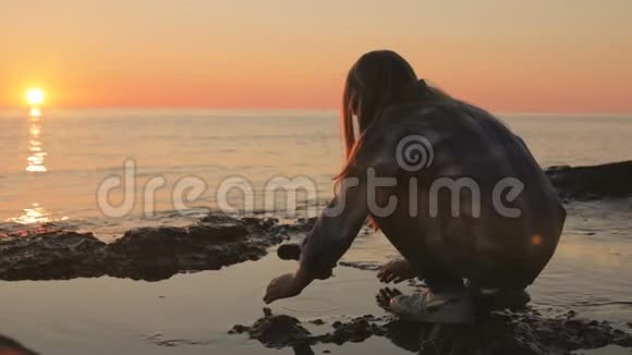 一个小女孩在海边用海水洗她的手和脸视频的预览图