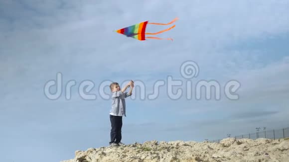 快乐可爱的小男孩带着彩色风筝在海边视频的预览图