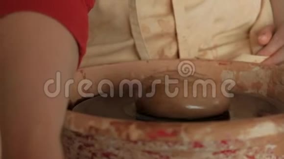特写女性双手将水滴在陶轮上的生泥上视频的预览图