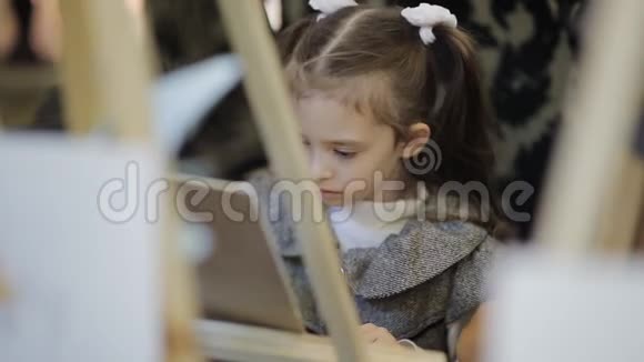 儿童美术工作室幼儿在画布上写图片桌子上有许多画架视频的预览图