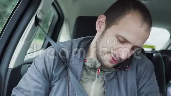 特写青年在汽车后座上用手机说话视频的预览图