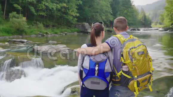 一对年轻夫妇欣赏山河拥抱女友的男人后景视频的预览图