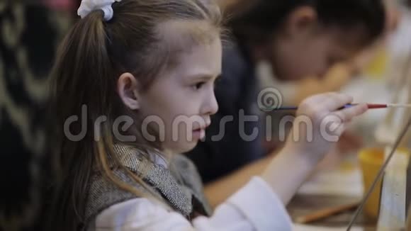 这个女孩在儿童美术工作室画一幅画桌子上有许多画架和画布视频的预览图