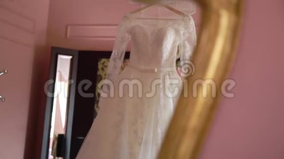 新娘晨间准备美丽的新娘穿着白色婚纱穿着睡衣抱着婚纱温柔时刻视频的预览图