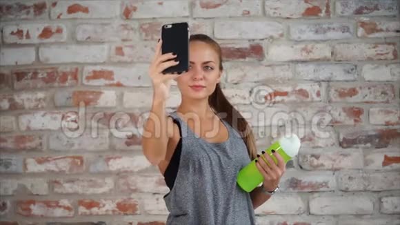 可爱的女人在电话里拍照女士手里拿着小瓶水视频的预览图