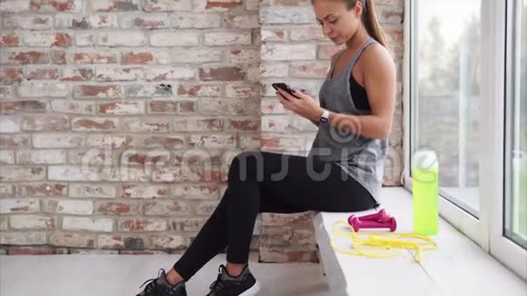 一位年轻女子最近在手机上参加体育活动检查社交网络视频的预览图