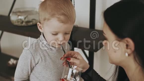 年轻的母亲和小儿子从家里的杯子里喝水视频的预览图