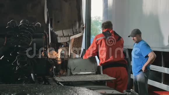 两位汽车修理工在汽车服务站谈论汽车发动机视频的预览图