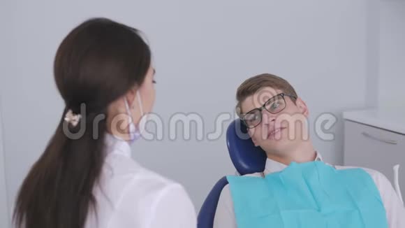 一位女牙医正在和坐在牙科椅上的病人交谈视频的预览图