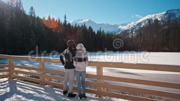 冬天年轻夫妇站在山湖附近看着兰斯卡普视频的预览图