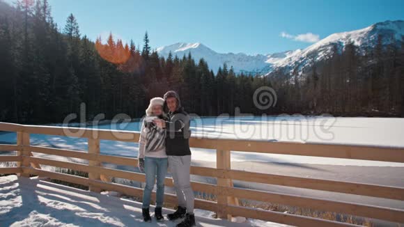 幸福的年轻夫妇在冬天的山区用智能手机户外活动视频的预览图