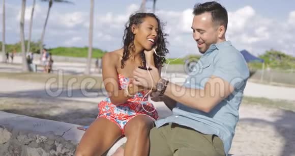 欢笑的夫妇在海边听音乐视频的预览图